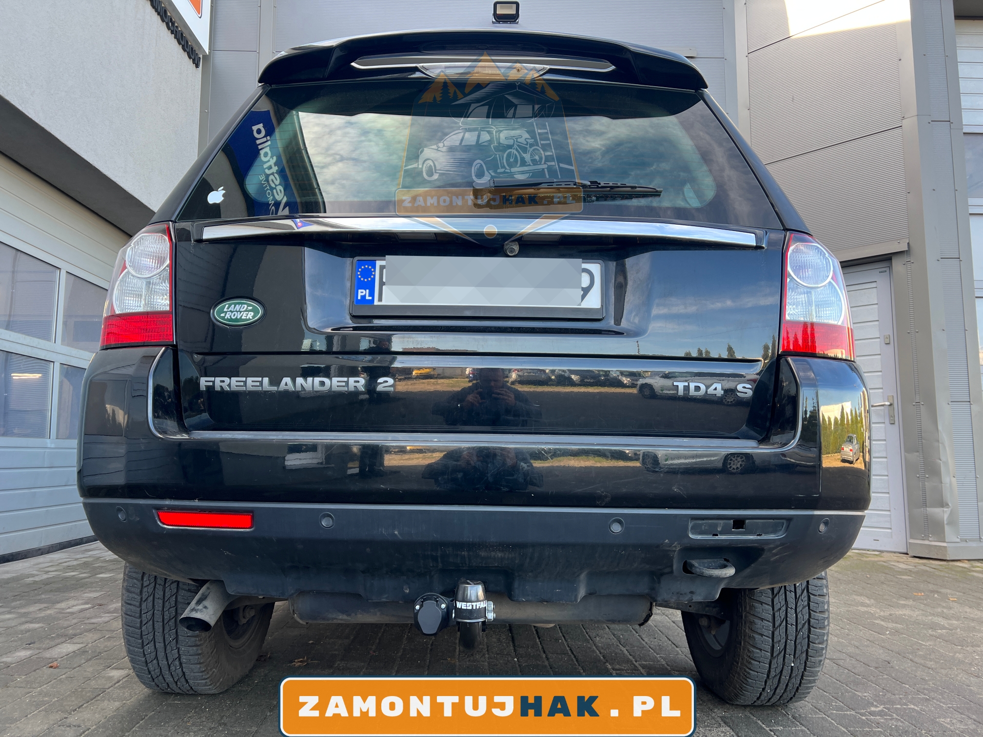 Zdjęcie samochodu Land Rover Freelander z zamontowanym stałym hakiem holowniczym Westfalia f20, zdjęcie zrobiono z tyłu samochodu na tle serwisu zamontujhak.pl 